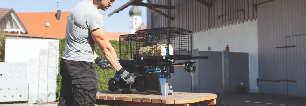 Person mit Gehörschutz und Holzspalter